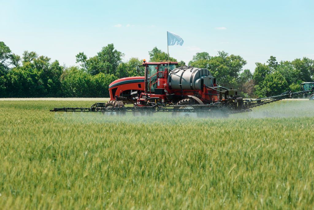 sprayer applying pesticide to wheat field